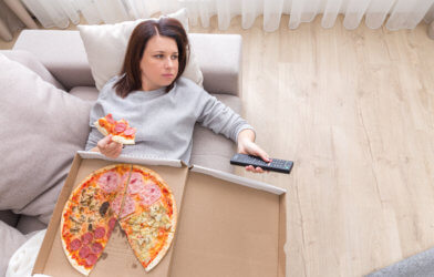 Woman eating pizza on the couch