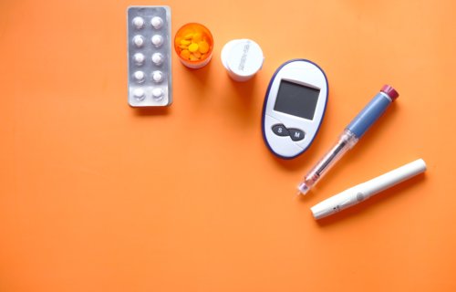 Insulin pen, diabetes measurement tools and pills on orange background